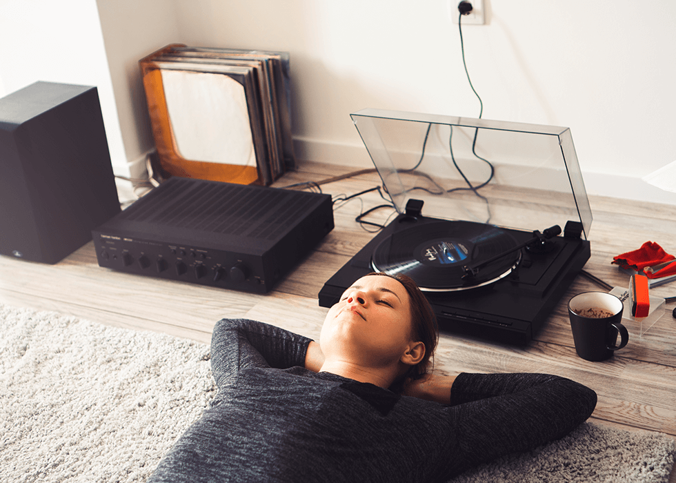 hi_fi_audio A young woman lying down listening to a record player.