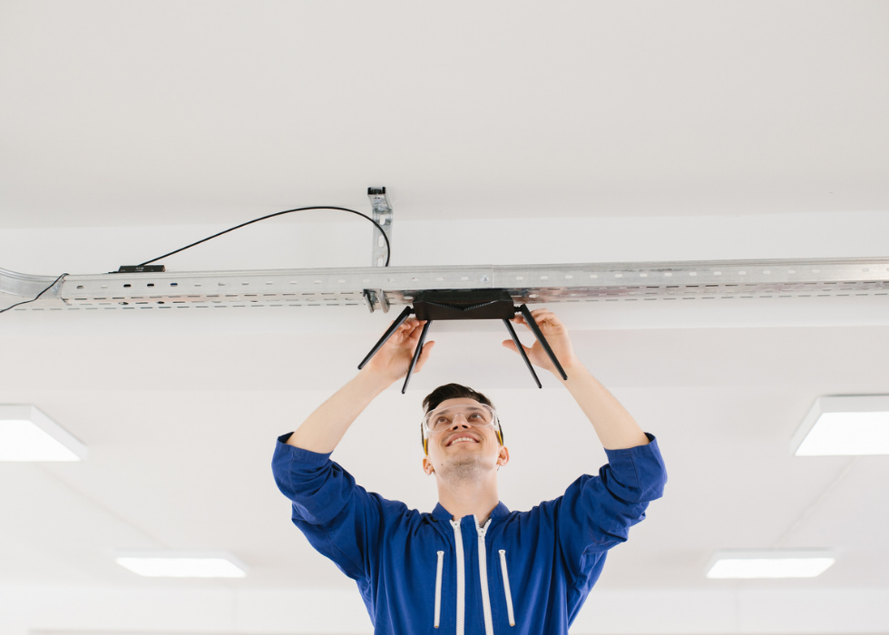 Technician installing wireless router into ceiling