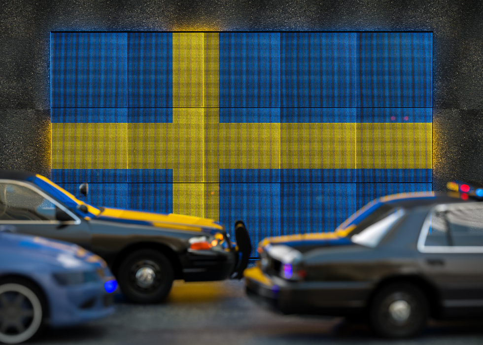 Bright digital display Sweden flag in city as cars drive past