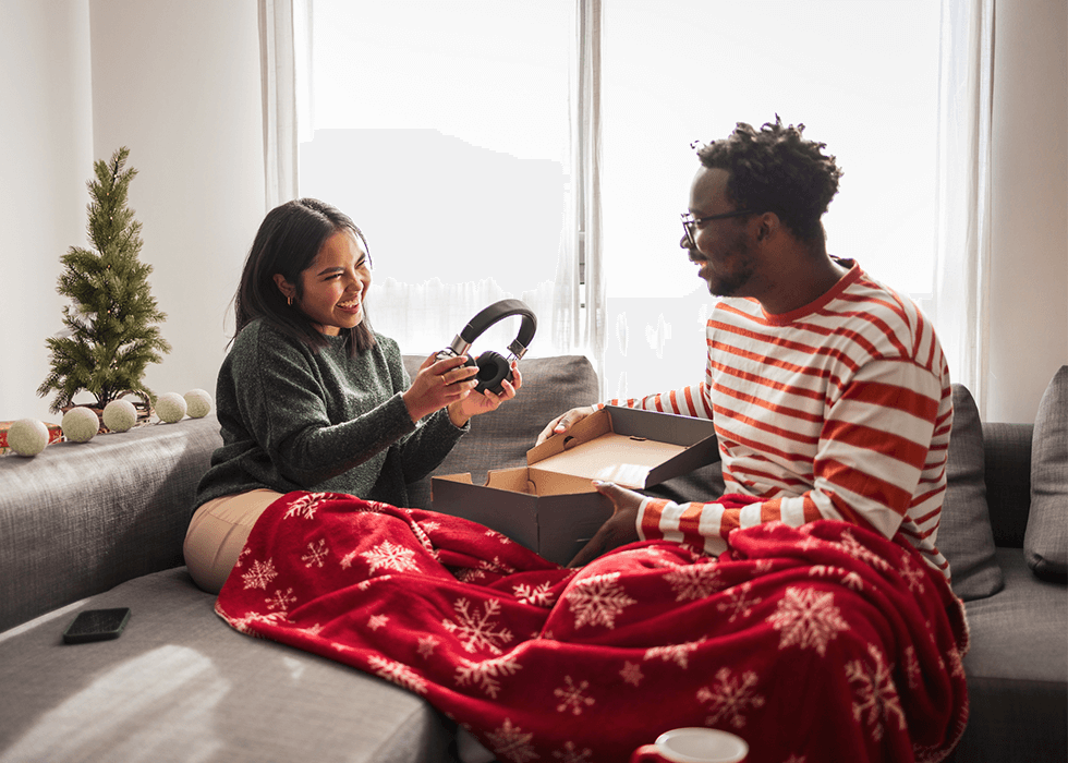 Two people exchanging gifts and woman holding headphones