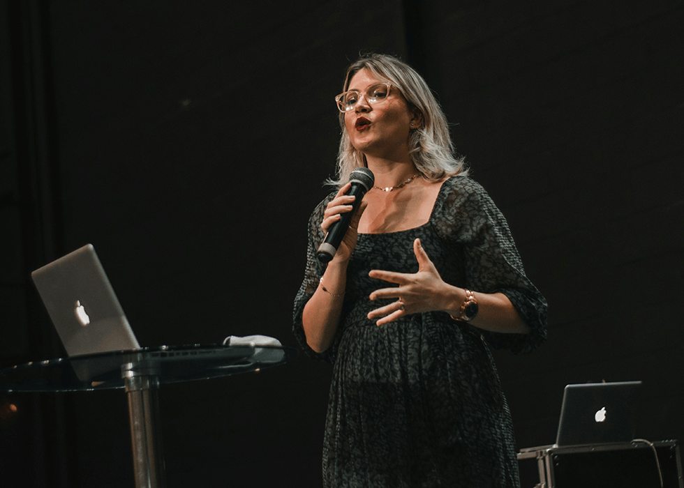 A woman on stage speaking with microphone