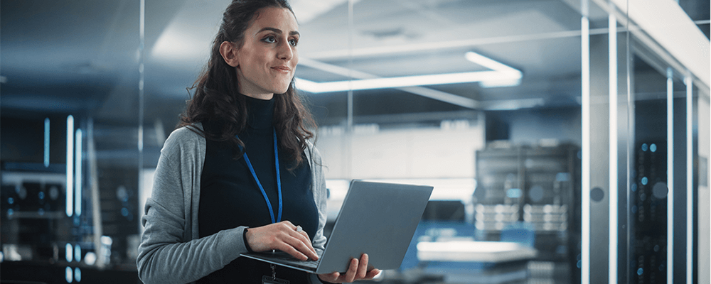 Woman holding laptop in glass office building