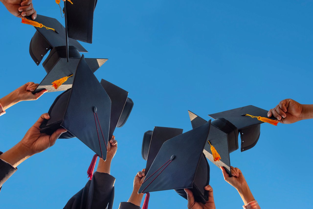 Graduation caps held up with blue background