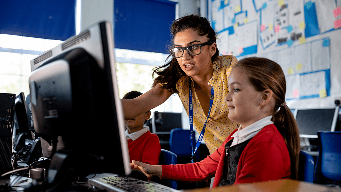 Woman showing a young girl something on the computer