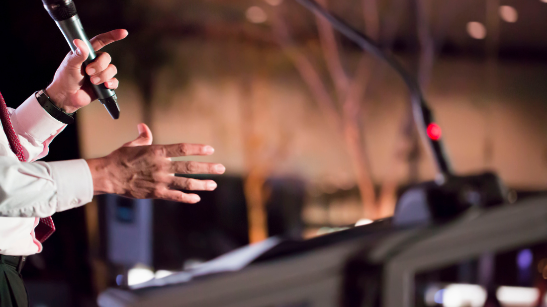 A man's hands holding a wireless mic on stage