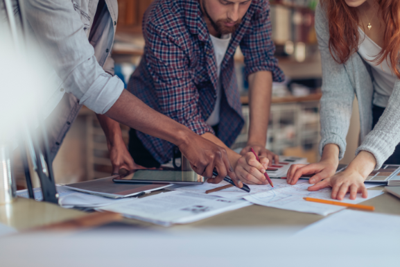 People around desk looking at architectural outlines