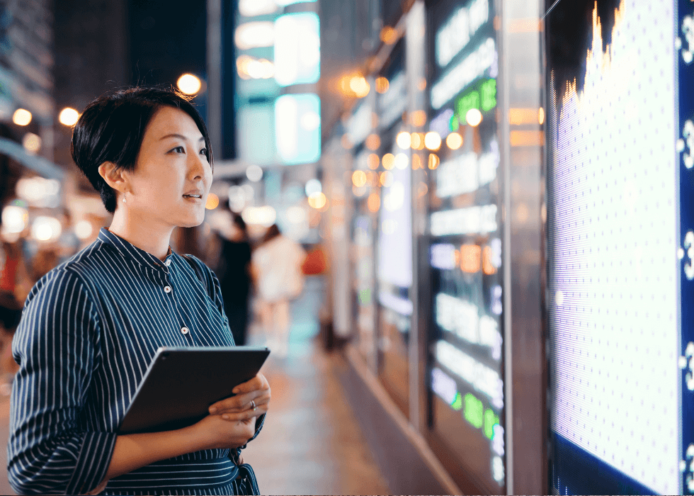 digital_signage_security Woman with tablet looking up at digital signage