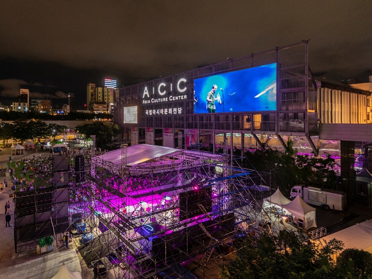 Large outdoor LED display screen on building facade at cultural venue during evening event