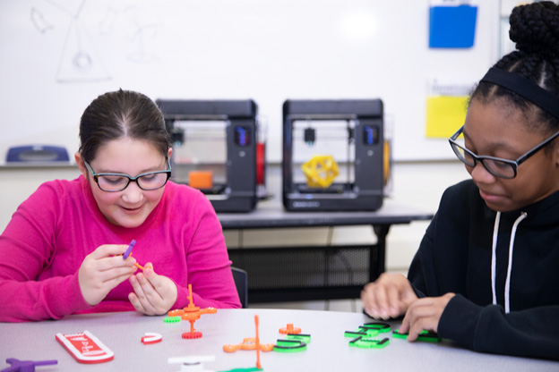 Students playing with 3D printers | AVIXA