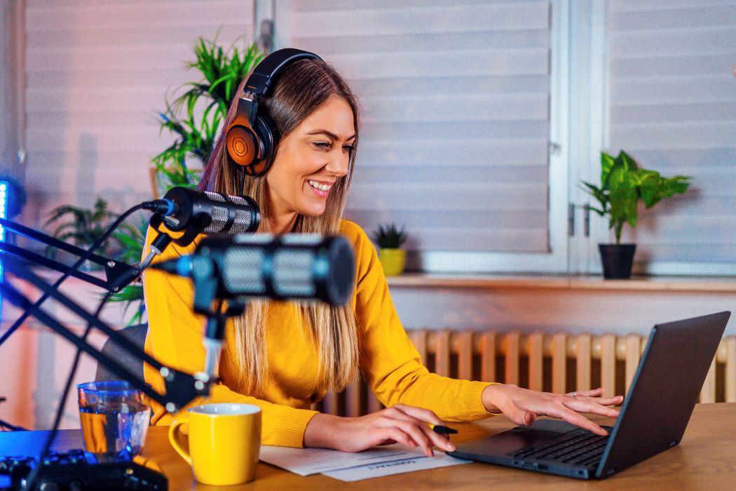Woman wearing headphones and yellow shirt on laptop